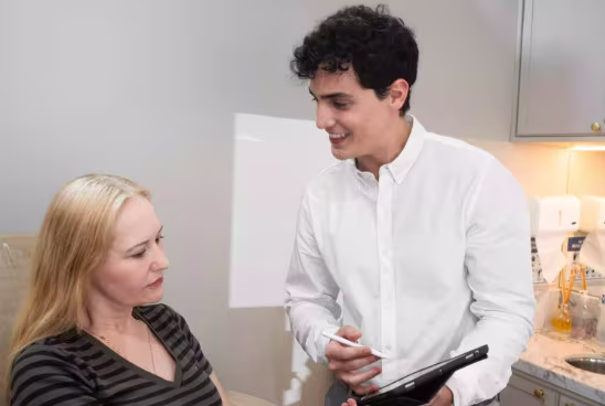 Dermatologista conversa com uma paciente durante avaliação de procedimentos estéticos.