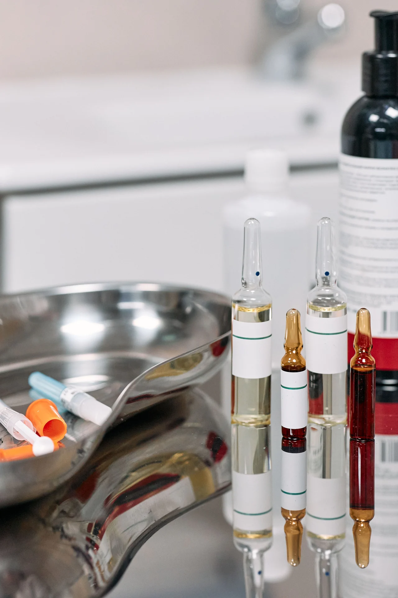 Imagem ilustrativa de ampolas e bandeja com materiais clínicos genéricos; marcas e produtos não identificados.