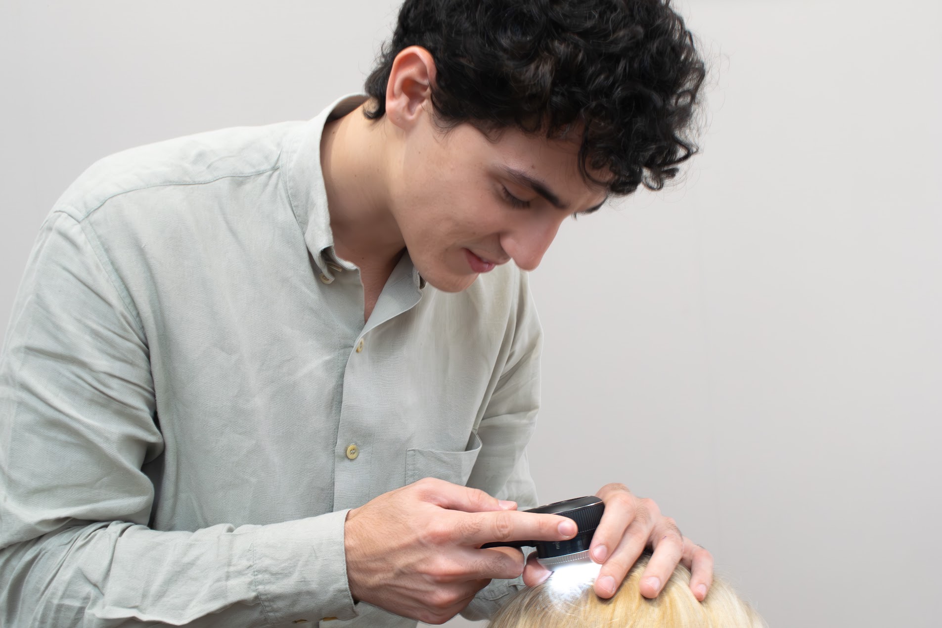 Dermatologista examina o couro cabeludo da paciente com um dermatoscópio.